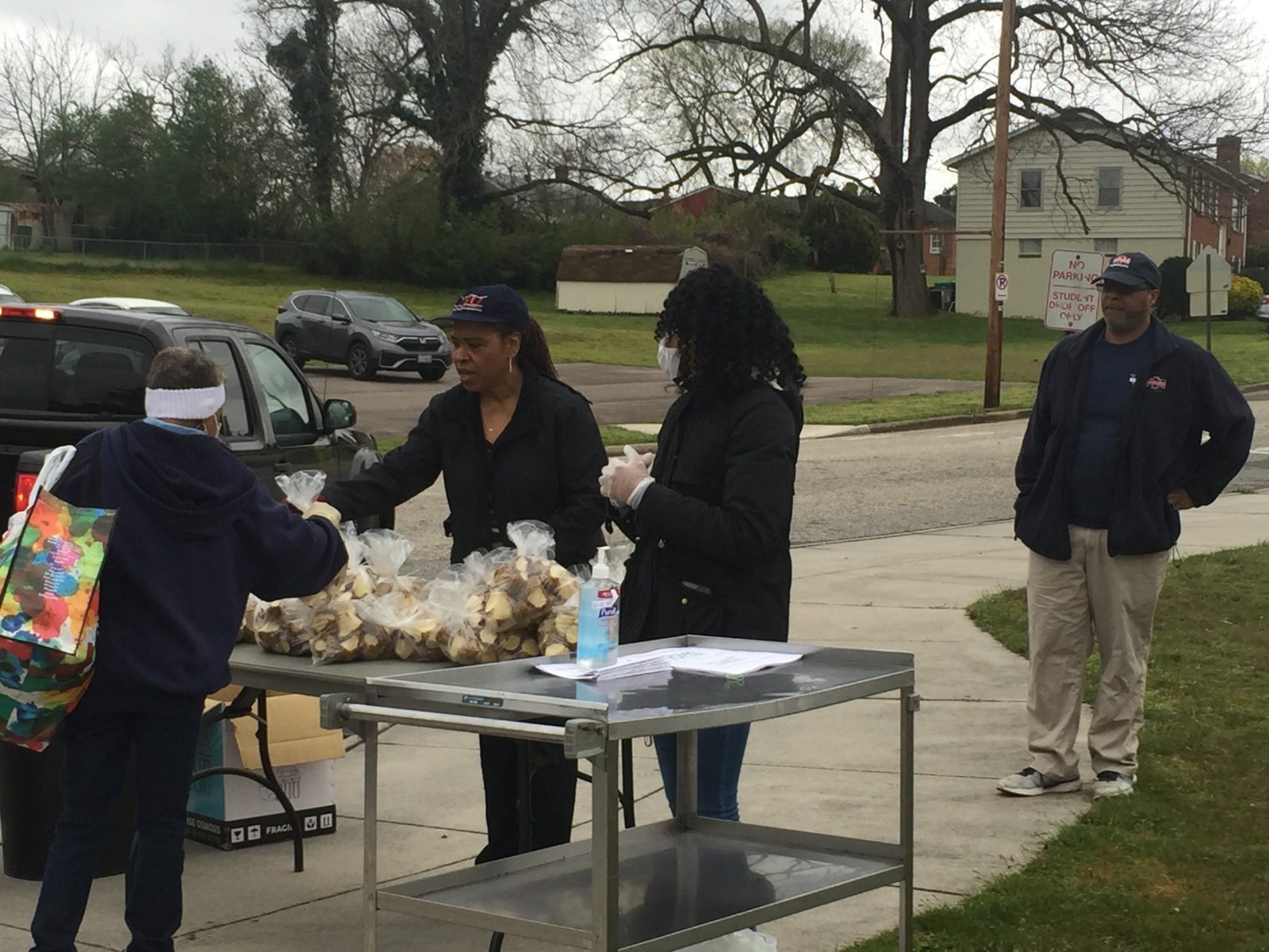 Food distribution volunteers hand out bags of cut up potatoes and recipe handouts