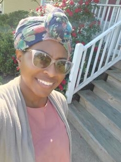 A smiling woman in a headscarf and sunglasses